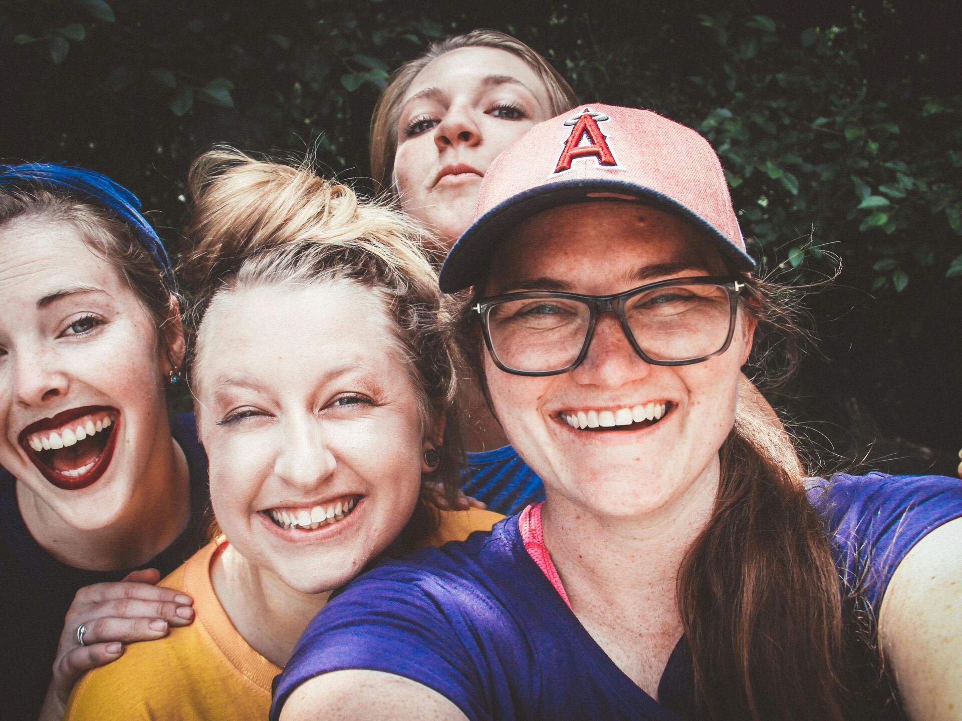 Drei lachende Personen machen im Freien ein Selfie und schauen fröhlich in die Kamera.